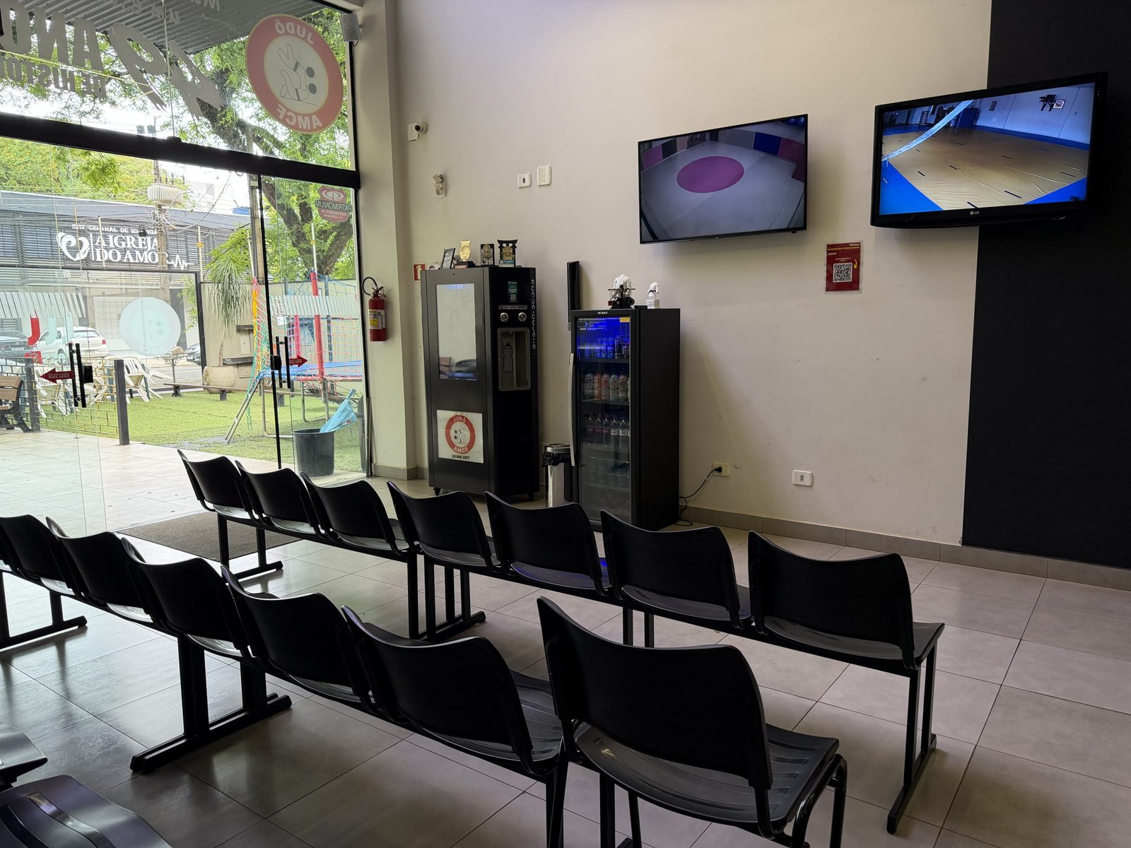 Espaço dos pais com TVs mostrando as câmeras do tatami